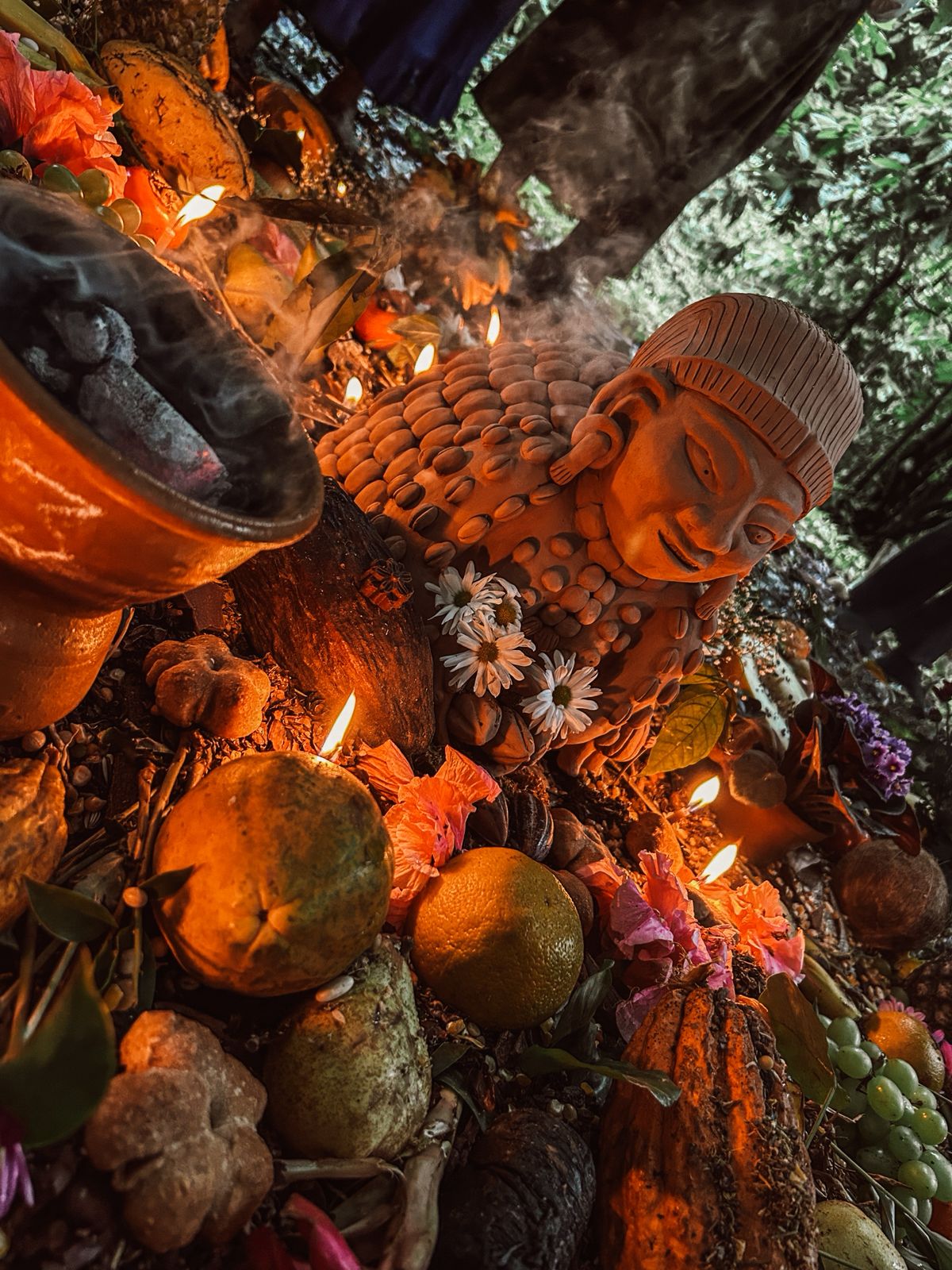 Altar maia com estátua do deus do cacau, frutas e velas