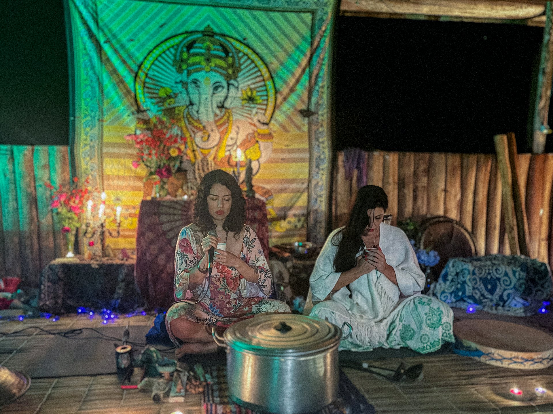 Duas mulheres em meditação profunda com tapeçaria de Ganesh ao fundo