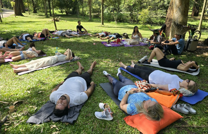 Participantes deitados na grama durante sessão de meditação e respiração