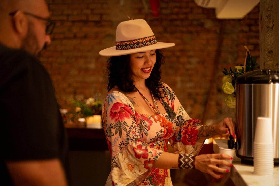 Melina Dau com chapéu florido preparando o cacau sagrado